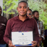 Raphaël Dingadia is posing for a picture at Baobab RDC after receiving his Certificate from David Muanda, CEO at Friendina College